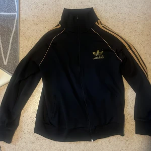 Svart Adidas track jacket med guldiga ränder - Använd men i bra skick