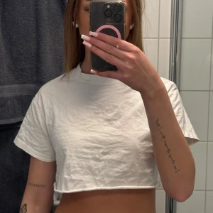 Vit croppad t-shirt från Bik Bok - Säljer en enkel och stilren vit croppad t-shirt från Bik Bok. T-shirten har korta ärmar och rund halsringning, perfekt till sommaren eller som basplagg i garderoben. Superenkel att matcha med allt!