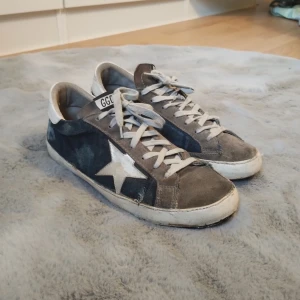 Grå och blå sneakers från Sievi - Säljer ett par sneakers från Golden Goosei i grått och blått med vit stjärndetalj på sidan. De har andra skulder än orginal (Sid 3) Dem är väl använda som ni ser på bild 4 och 5 så därför så är de jättebilliga. OBS de är Äkta!