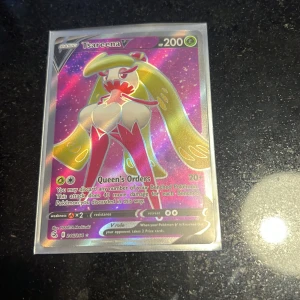 Pokémonkort: Tsareena V & Mewtwo - Två coola Pokémonkort! Tsareena V är ett glittrande kort med 200 HP och attacken Queen's Orders. Mewtwo-kortet har en stilren, blå design. Perfekt för dig som samlar eller spelar Pokémonkort och vill ha något unikt i din samling.