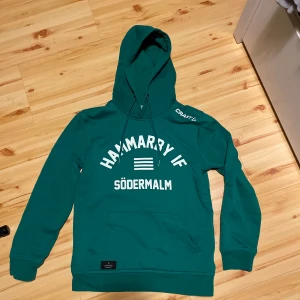Grön Hammarby IF hoodie från Craft - Säljer en grön hoodie från Craft med Hammarby IF Södermalm-tryck på bröstet. Tröjan har huva med dragsko och en stor magficka. Perfekt för dig som vill visa ditt stöd för Hammarby!