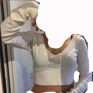 Vit croppad stickad tröja från Bershka - Säljer en vit croppad stickad tröja från Bershka med v-ringning och långa ärmar. Tröjan har bred ribbad mudd vid ärmslut och nederkant, vilket ger en snygg och modern look. Perfekt att styla med höga jeans eller kjol. Har inte magtröjor Drf aldrig använd. Passar för S,M och L. 