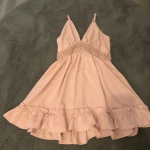 Ljusrosa volangklänning från Cider - Supersöt ljusrosa kortklänning från Cider med smala axelband, v-ringning och fina volangdetaljer nertill. Klänningen har spetsdetaljer under bysten och en luftig passform, perfekt för varma dagar. Klänningen är ganska kort på mig som är 167 skulle rekommendera för nån som är 155-160.