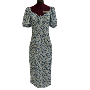 Blommig blå och vit klänning med puffärm - Söt midi klänning med blått blommönster på vit botten. Modellen har puffärmar, v-ringning med knyt och en smickrande midilängd. Perfekt för sommarens alla tillfällen. Materialet känns lätt och luftigt. Endast använd en gång. (Ca 110 cm lång, 65cm i midja och 85cm i byst, men stretchigt material)