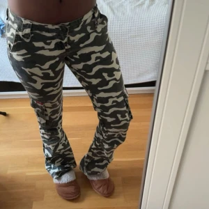 Lågmidjade camouflage byxor  - Säljer ett par lågmidjade jeans i klassiskt grönvitt camouflage. Storlek 27, jag brukar ha 34/36 i byxor och jeans🌼