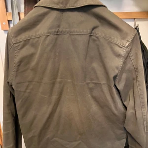Olivgrön overshirt från J.Lindeberg - Säljer en olivgrön overshirt från J.Lindeberg med tre stora fickor framtill och klassisk krage. Jackan har knäppning med svarta knappar och är tillverkad i ett kraftigare bomullstyg. Perfekt för lager-på-lager. Tveka inte att skriva om ni har några funderingar!! 