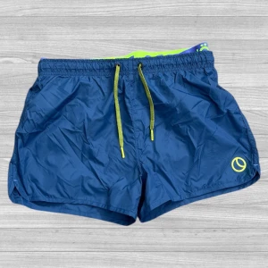 Björn Borg badshorts - Snygga blå badshorts från Björn Borg med neongula detaljer och snörning i midjan. Shortsen har elastisk midja och ett litet Björn Borg-tryck på benet. Perfekta för stranden eller poolen.
