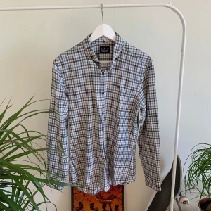 Rutig skjorta från River Island - Rutig skjorta med långa ärmar och knappar framtill. Skjortan har en button-down krage och en broderad logotyp på bröstet.   Storlek M
