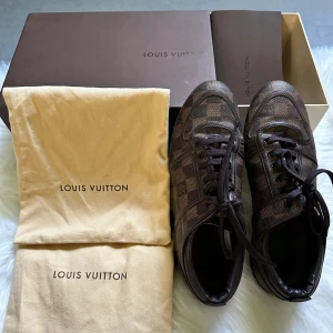 Bruna sneakers från Louis Vuitton - Säljer ett par bruna Louis Vuitton sneakers i klassiskt rutigt mönster. Skorna har snörning och är tillverkade i skinn med LV-logga på sulan. Kommer med originalkartong och dustbags kvitto.Perfekta för dig som gillar lyxiga detaljer och tidlös design.