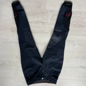 Mörkblå ridbyxor med silikonprint från Euro-Star - Svarta ridbyxor från Euro-Star med helskodd silikonprint för extra grepp. Byxorna har hög midja och diskreta röda logodetaljer. Tillverkade i stretchigt syntetmaterial för maximal rörelsefrihet.