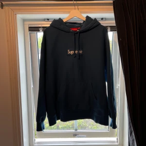 Supreme hoodie - En stilren hoodie från Supreme med en broderad logotyp på bröstet och årtalet 2023 broderat på baksidan. Hoodien har en klassisk passform med en justerbar huva och en känguruficka.  Mått 📏:  Bröstvidd: ca 68 cm  Längd: ca 70cm Arm längd: 55 cm   Hör av dig vid frågor! 