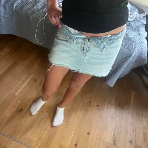 Ljusblå jeanskjol från Hollister - Säljer en ljusblå jeanskjol från Hollister med rå, fransig kant nertill och klassiska femficksdetaljer. Baksidan har en svart stjärna  på ena fickan. Perfekt för dig som gillar en avslappnad och trendig stil. ‼️LITEN I MIDJAN‼️