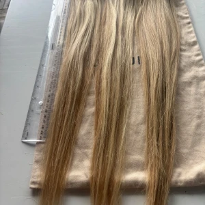 Äkta premium hår 63 cm  - Äkta premium hår. 63 cm. Ca 120 g. Långa, raka löshår clips i ljusblond färg med naturliga skiftningar. Perfekt för att ge extra längd och volym till håret. Fästes enkelt med clips längs hårbotten. Clips skickas med. 