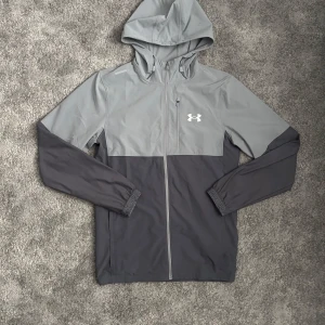 Under Armor vindjacka -  Säljer nu en snygg tunn under armor vindjacka, Jackan är i jättefintskick föurom att den har någon liten fläck som du kan se på sista bil (går säkert bort i tvätten)✅hör gärna av dig vid frågor🙌🏼 