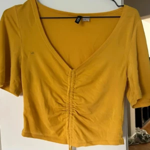 Gul topp - En jätte fin gul topp som man kan dra upp i mitten med hjälp av snöre, och volang i armarna! Tyvärr en fläck (som ses på bild) därav det låga priset!💕