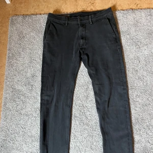 Svarta byxor - Säljer ett par svarta byxor från Replay med klassisk passform. Byxorna har snedställda fickor fram och passpoalfickor bak. Stängs med dragkedja och knapp. Perfekta till både vardag och mer uppklädda tillfällen.