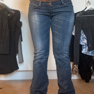 Blå bootcut jeans med lågmidja  - Säljer ett par blå bootcut lågmidjade jeans med unika dragkedjor på bakfickorna.