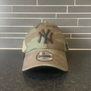 Camouflage keps från New Era Yankees - Säljer en klassisk 9FORTY keps från New Era med New York Yankees-logga framtill. Kepsen har camouflage-mönster i gröna och bruna toner samt böjd skärm. Justerbar passform baktill och broderad logga. Storlek Youth! Hör av dig vid funderingar 😊