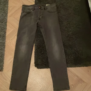 Mörk gråa jeans från Diesel Tepphar - Säljer ett par svarta Diesel Tepphar jeans med slim passform och stretch. Klassisk femficksmodell med diskreta slitningar och raka ben. Perfekta för dig som gillar en smalare siluett och vill ha bekväma jeans till vardags.
