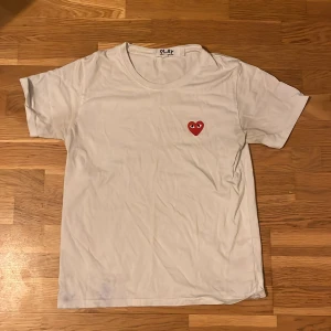 Cdg T-shirt Vit  - En vit cdg T-shirt som är perfekt till sommaren. Små defekter där lappen i nacken är lös men går enkelt att fixa på 1 minut genom att sy. Storlek L men är liten i storlek och är mer som S. Nypris 949kr. Skriv vid minsta fundering! ✅