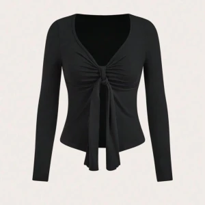 Svart långärmad topp med knyt - Snygg svart långärmad topp med v-ringning och knyt framtill. Figurnära passform som framhäver midjan och ger en stilren look. Perfekt att styla med jeans eller kjol