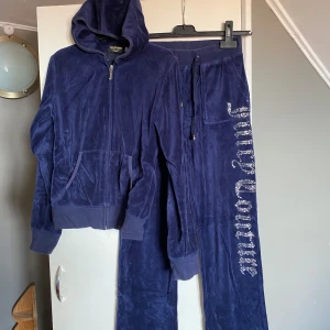 Mörkblå velourbyxor från Juicy Couture - Mörkblå velourbyxor från Juicy Couture med glittrig logga längs benet. Byxorna har dragsko i midjan. Använd ett fåtal gånger.