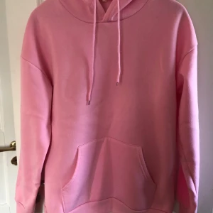 Rosa hoodie med ficka - Säljer en enkel och snygg rosa hoodie med huva och dragsnören. Tröjan har en stor magficka och långa ärmar i storlek s 🩷
