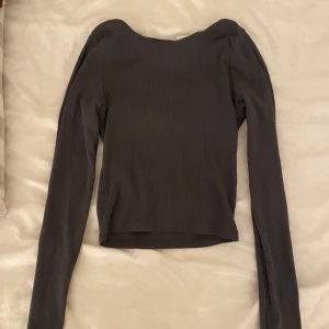 Mörkgrå  ribbad långärmad topp från H&M Divided - Säljer en mörkgrå långärmad topp från H&M Divided i storlek XXS. Toppen är ribbad och har en tight passform, perfekt att styla till olika outfits. Enkel och stilren design som passar till mycket.