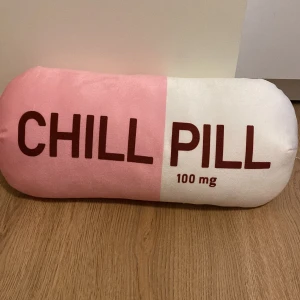 Chill pill kudde - En mjuk kudde med texten ”chill pill” ena sidan är rosa och den andra är vit, perfekt för att ha i sängen eller soffan