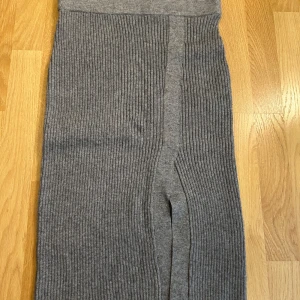 Grå ribbad kjol från Vila - Grå ribbad kjol från Vila i stickad kvalitet. Den är stretchiga och har en snygg, enkel look som passar till allt. Kjolen har även en slits framtill.❤️