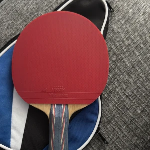 pingisracket -  ett pingisracket av märket Yasaka med tillhörande fodral. Racketen har en röd och en svart sida, båda märkta med 'Vision Yasaka'. Perfekt för dig som vill ta ditt bordtennisspel till nästa nivå, oavsett om du är nybörjare eller mer erfaren.