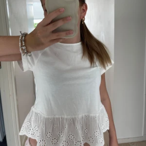 superfin sommartopp! 🤍 - Supersöt vit blus med korta ärmar och volang nertill. Volangen har broderade blommor och hålmönster💗 Toppen är i tunn bomull och är lite kortare vid magen men det är så fint, ja säljer på grund av att jag inte har jättemycket användning av den ! 