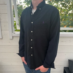 Svart Ralph lauren skjorta - Säljer fin Ralph Lauren skjorta, inga tecken på användning och väldigt bra skick, postas inom 48h och modellen är slim fit, bara att skriva vid funderingar👍