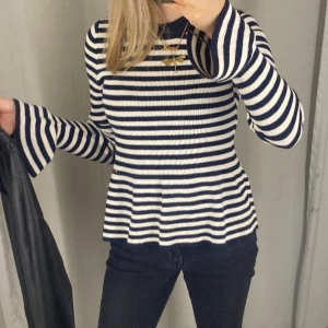 Randig stickad tröja med utsvängda ärmar - Säljer en snygg stickad tröja med marinblå och vita ränder. Tröjan har långärmade, utsvängda ärmar och en lätt figurnära passform. Perfekt för dig som gillar en klassisk men trendig look. Superfin till jeans eller kjol!
