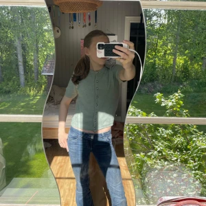 Ljusgrön stickad kofta från H&M - Superfin ljusgrön stickad kofta från H&M med kort ärm och snygga silvriga knappar framtill. Modellen är croppad och har en rund halsringning. Perfekt att slänga på sig över ett linne eller t-shirt för en chill look.