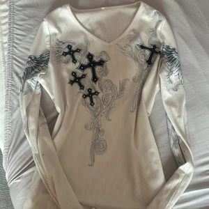 Vit tröja med kors  - As sexy tröja med kors på :3 Köpt här på plick. Står inte storlek men jag är XS-S och den ser ut så på mig. Är rätt så stretchig så skulle kunna massa M 