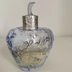 Lolita Lempicka Eau de Toilette 30ml - Parfym från Lolita Lempicka i form av ett äpple med ljusblått glas, silverdetaljer och gnistrande stenar. Doften är mycket "puderig" vilket är en tröstande och mysig doft. Flaskan har en unik, sagolik desig.. Perfekt för dig som älskar snygga flaskor! Top notes are Cherry, Apricot and Lemon; middle notes are Iris and Jasmine Sambac; base notes are Violet, Musk and Incense.