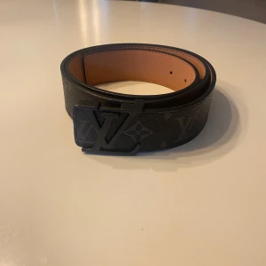 Svart bälte med monogram - Snyggt svart bälte i skinn. Bältet har en bred design och insidan är beige. Perfekt accessoar för att lyfta din outfit med exklusiv känsla och ikonisk stil.