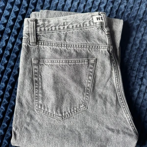 HOPE Rush Jeans - Snygga grå jeans från HOPE med klassisk femficksdesign och raka bakfickor. Jeansen har en ljusgrå tvätt och är tillverkade i ett robust jeanstyg. Perfekta för dig som gillar en stilren och enkel look.