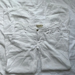 Vita linnebyxor - Snygga vita linnebyxor från ICHI med coola detaljer som silverfärgade nitar och ett gulligt rosa märke där bak. Byxorna är lågmidjade!