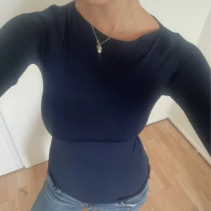 Mörkblå tight långärmad tröja - Säljer en mörkblå långärmad tröja med tight passform och rund halsringning. Tröjan är enkel och stilren, perfekt att matcha med jeans eller kjol. Materialet känns mjukt och stretchigt, vilket gör den bekväm att bära hela dagen.