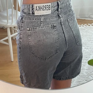 Gråa jeansshorts från Bershka - Coola gråa jeansshorts från Bershka med hög midja. De har en lite lös passform. Skiftar i färg, lite mörkare nertill. Snygg till en oversized tröja om man inte alltid känner för färgskillnaden. 