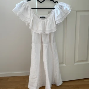 Vit  klänning  - Superfin vit kortklänning med bred volang runt axlarna 🤍Passar mig som brukar ha S! Använd en gång.