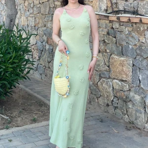 Ljusgrön långklänning med 3D-blommor oanvänd  - Superfin ljusgrön långklänning med smala axelband och v-ringning. Klänningen har dekorativa 3D-blommor över hela framsidan och är figurnära med en mjuk, stickad känsla. Perfekt för sommarens alla tillfällen!