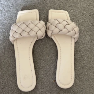 Beige flätade sandaler med fyrkantig tå - Snygga sandaler i ljusvit färg med bred, flätad rem över foten och fyrkantig tå. Platt sula och stilren design som passar perfekt till sommarens outfits. Tillverkade i syntetmaterial för en modern look. Super sköna och passar till mycket. Helt oanvända!!♥️