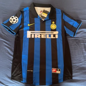 Inter Ronaldo 9 Nike fotbollströja S - Inter Milan fotbollströja med Ronaldo 9 på ryggen. Klassisk blå och svart randig design, officiellt klubbmärke och Champions League-märke på ärmen. Tillverkad i lätt och ventilerande polyester, med Pirelli som sponsor och gul Nike-logga på bröstet.