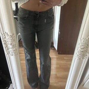 Bootcut jeans med broderad bakficka - Säljer ett par grå jeans med snyggt broderi och små glittriga stenar på ena bakfickan. Jeansen är i modellen bootcut och sitter low/mid waist