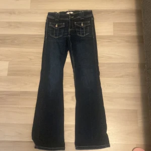 Mörkblå bootcut jeans Gina Tricot 152 - Snygga mörkblå jeans från Gina Tricot i storlek 152. Modellen har bootcut-ben och coola fickdetaljer framtill med knappar. 
