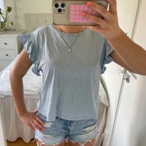 Ljusblå T-shirt med volangärmar - Supersöt ljusblå t-shirt med volangdetaljer på ärmarna och rund halsringning. Modellen är lite loose och  perfekt till jeansshorts eller kjol. Tunn och skön i bomull, passar perfekt för varma dagar. Tröjan är från Zara och säljer för 65kr❣️ i nyskick ❤️ i storlek M men passar mer som S🌟 säljer samma fast i vit!🤍