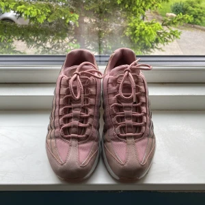 Råsa Air Max 95 - Säljer ett par Nike Air Max 95 i en snygg rosa färg. Skorna har en chunky vit sula med synliga Air-enheter, ovandel i mesh och mocka samt coola vågiga paneler. Klassisk snörning och broderad Air Max-logga på plösen. Perfekta för dig som vill sticka ut med dina sneakers.